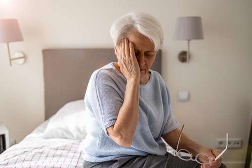 Elder woman with Migraine, sitting on the bed